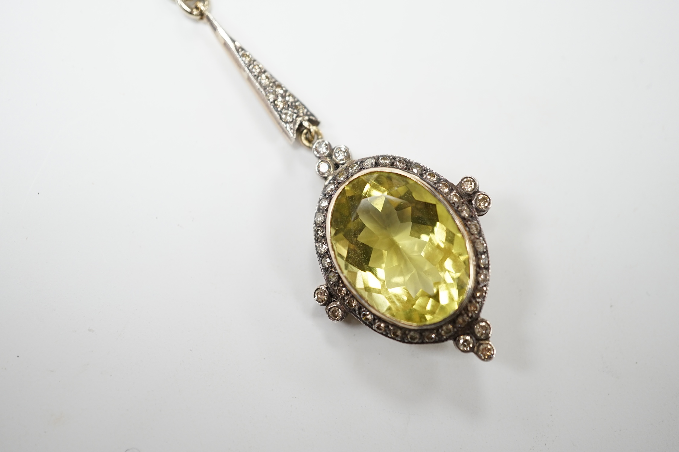 A late Victorian yellow metal and single stone oval cut citrine set drop pendant, with diamond set border and bale, 53mm, on a later 375 white metal chain, 50cm, gross weight 11.2 grams. Good condition.